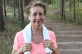 Close Up Of Senior Woman Running In Park Listening To Music Holding a Towel Royalty Free Stock Photo