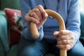 Close Up Of Senior Woman Sitting In Chair Holding Walking Cane