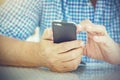 Close up of seniors hands holding and typing text message on smartphone, blue shirt