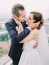 The close-up sensitive portrait of the happy newlyweds touching the faces of each other.