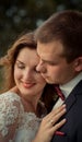 Close-up sensitive wedding portrait of the pretty smiling newlyweds softly hugging.