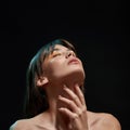 Close up of sensuous young brunette woman with professional makeup touching her neck, posing with eyes closed isolated Royalty Free Stock Photo