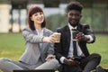 Close up serious businessman and businesswoman drinking take away coffee sitting on the grass Royalty Free Stock Photo