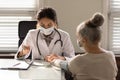 Close up doctor wearing mask measuring old woman blood pressure