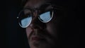 Close up of serious focused man scientist face in glasses looking at screen in the dark room. Concept. Male reading Royalty Free Stock Photo