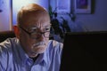 Close up of serious older man using home computer, horizontal Royalty Free Stock Photo