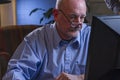 Close up of serious older man using home computer, horizontal Royalty Free Stock Photo