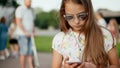 Close up serious teenage girl browsing smartphone in summer park Royalty Free Stock Photo