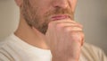 Close-up of serious young man with beard rubbing chin, having doubts, thinking Royalty Free Stock Photo