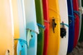 Close up Set of different color surf boards with fins in a stack on sandy beach for rent. Multicolored surfboards as Royalty Free Stock Photo