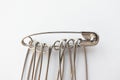 Close-up set of metall safety pins for crafts, fashion, jewelry, hobby or household on white background. Isolated object, Royalty Free Stock Photo