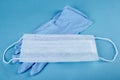 Close-up of set of nurse gloves and a medical mask on a blue background. protection from coronavirus