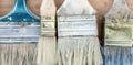 Close-up set of old used pant brushes on rustic wooden background. Vintage dirty paintbrushes