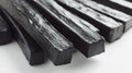 A close-up of several black, rectangular licorice sticks arranged on a white surface Royalty Free Stock Photo
