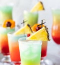 Close up of several colourful icy cocktails garnished with pineapple wedges.