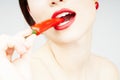 Close up of a woman biting a chili pepper