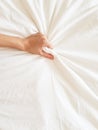 Close up sexy woman hand pulling and squeezing white sheets in ecstasy in bed. Orgasm on white bed. Sex and erotic