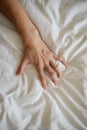 Close up sexy woman hand pulling and squeezing white sheets in ecstasy in bed. Orgasm on white bed. Sex and erotic