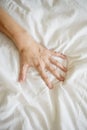 Close up sexy woman hand pulling and squeezing white sheets in ecstasy in bed. Orgasm on white bed. Sex and erotic Royalty Free Stock Photo