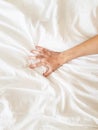 Close up sexy woman hand pulling and squeezing white sheets in ecstasy in bed. Orgasm on white bed. Sex and erotic