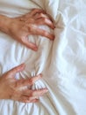 Close up sexy woman hand pulling and squeezing white sheets in ecstasy in bed. Orgasm on white bed. Sex and erotic