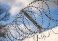 Close up sharp pointed razor wire barb fence coiled on top of prison wall keeping secure prisoners in and criminals out Royalty Free Stock Photo