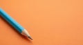 Close Up of a Sharpened Blue Pencil Lying on an Orange Surface writing Royalty Free Stock Photo