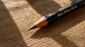 Close-up of a sharpened pencil tip resting on a textured surface with dappled sunlight Royalty Free Stock Photo