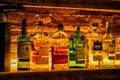 Close-up of a shelf of various types of alcoholic beverage bottles illuminated with light in a bar Royalty Free Stock Photo