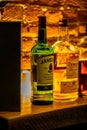 Close-up of a shelf of various types of alcoholic beverage bottles illuminated with light in a bar