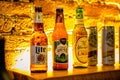 Close-up of a shelf of various types of alcoholic beverage bottles illuminated with light in a bar