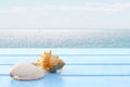 Close up shells on blue wooden table have blur sea view for background, concept summer on the beach