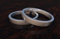 Close Up of 2 Shinny Silver Rings on Woodenbase