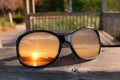 Close up of shiny black sunglasses on railing of gazebo with sunset reflecting in lenses Royalty Free Stock Photo