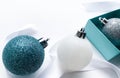 Close-up of shiny Christmas balls blue turquoise, white and silver color with ribbon and blue gift box on a white background. The Royalty Free Stock Photo