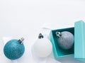 Close-up of shiny Christmas balls blue turquoise, white and silver color with ribbon and blue gift box on a white background. The Royalty Free Stock Photo