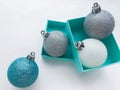 Close-up of shiny Christmas balls blue turquoise, white and silver color with ribbon and blue gift box on a white background. The Royalty Free Stock Photo