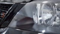 Close-up of shiny new car headlight. Action. Clean headlight with reflection and shine of black new car ready to buy