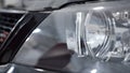 Close-up of shiny new car headlight. Action. Clean headlight with reflection and shine of black new car ready to buy