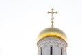 Close-up of shiny sunlit christian church dome with cross on top against white sky Royalty Free Stock Photo