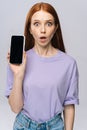 Close-up of shocked young woman in casual clothes holding cell phone with black empty mobile screen. Royalty Free Stock Photo