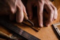 Close up of a shoemaker or artisan worker hands. Leather craft tools on old wood table. Leather craft workshop.