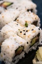 A close-up shoot of Uramaki sushi rolls with fresh salmon, avocado and philadelphia cheese, covered with sesame seeds