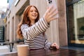 Close-up shooting from below of happy young woman looking at smartphone screen with smile, enjoying video call outdoors Royalty Free Stock Photo