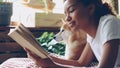 Close-up shot of African American girl dog owner reading book lying on bed in modern flat near adorable obedient pet