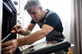 Close up shot of aged repairman in uniform working, fixing broken oven in the kitchen using screwdriver. Repair service