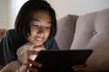 Close up shot of asian little girl using tablet while lying watch video on the sofa smiling and expression on her face in the Royalty Free Stock Photo