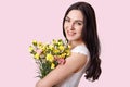 Close up shot of attractive woman with make up, natural beauty, gentle smile, has long straight hair, carries flowers, recieves