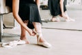 Close-up shot of a ballerina taking off the ballet shoes sitting on the floor in the studio Royalty Free Stock Photo