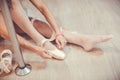 Close-up shot of a ballerina taking off the ballet shoes sitting on the floor in the studio near the pole Royalty Free Stock Photo